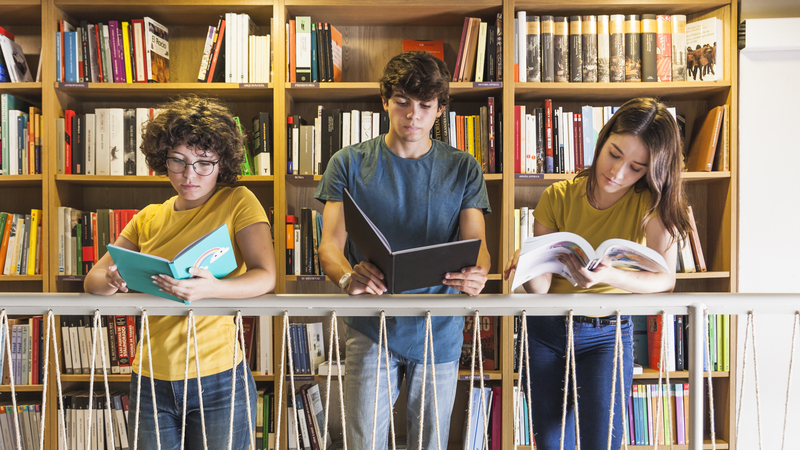 Focused Teenagers Reading Book Near Railing