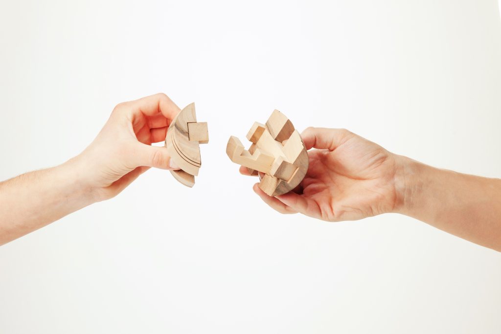 The Wooden Puzzle In Male Hand Isolated On White Background